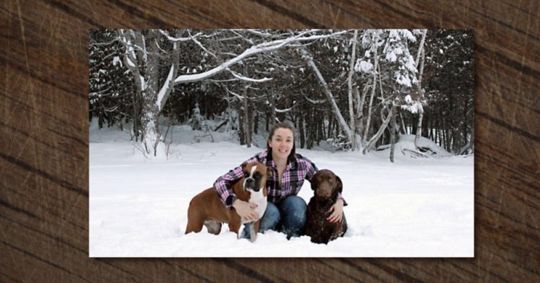 Samantha Randall sitting outside in the snow with two rescue dogs.