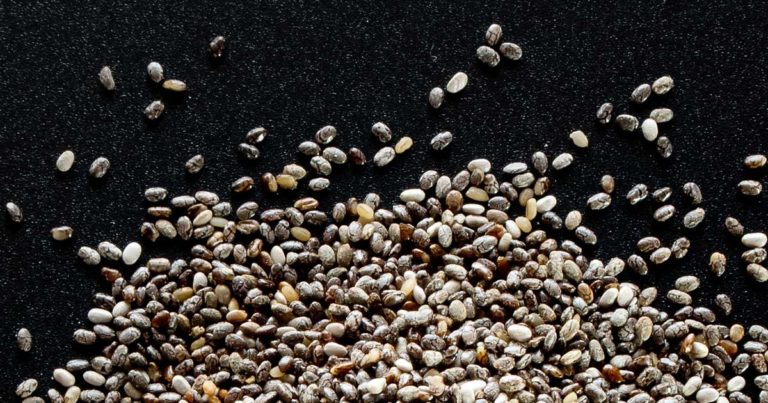 Different varieties of grains lying in a pile on a black surface.