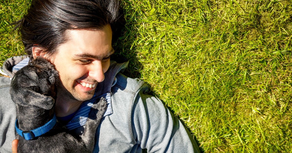 Close-Up of Man Lying on Grass with Dog | Diamond Pet Foods