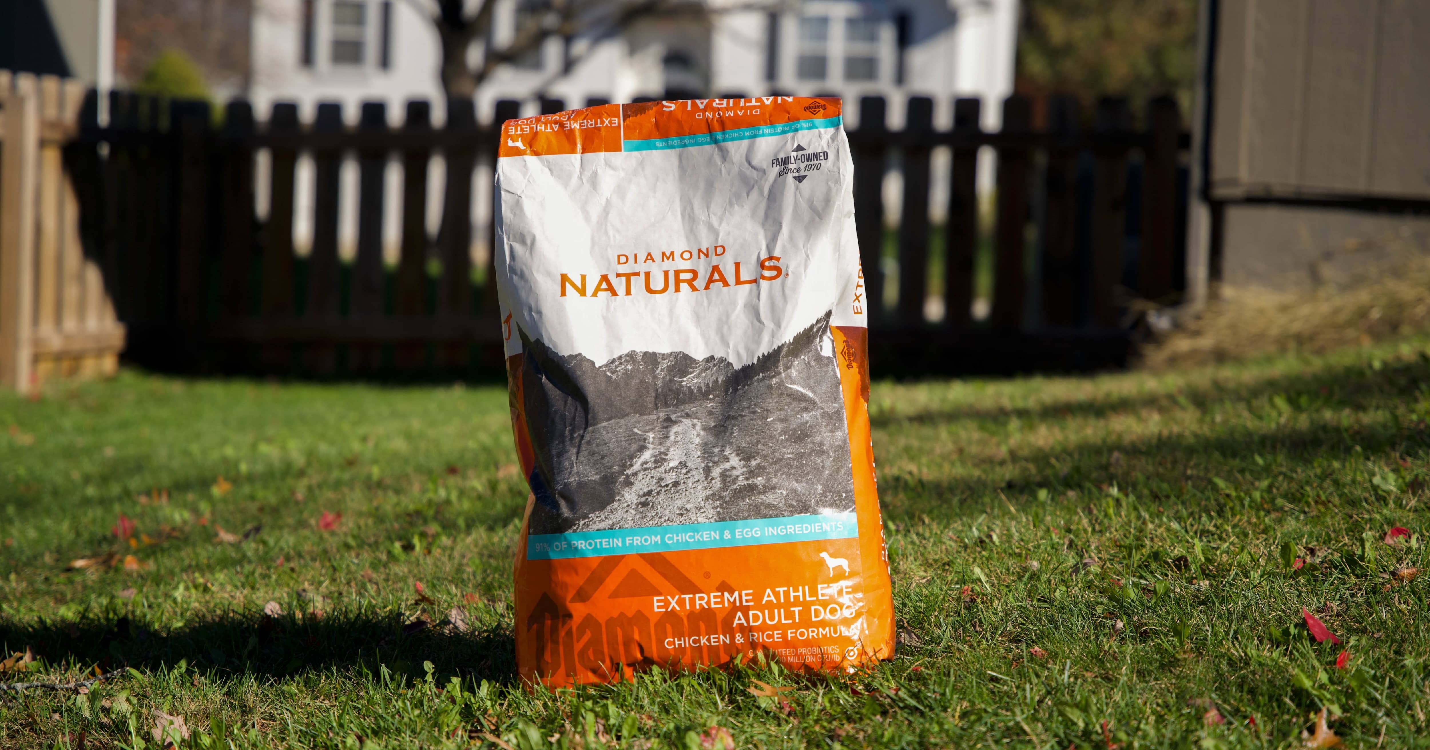 A bag of Diamond Naturals Extreme Athlete Adult Dog Chicken & Rice Formula sitting in green grass on a sunny day.