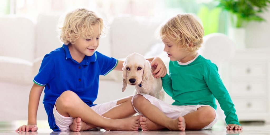 Two children sitting on the floor playing with a puppy.