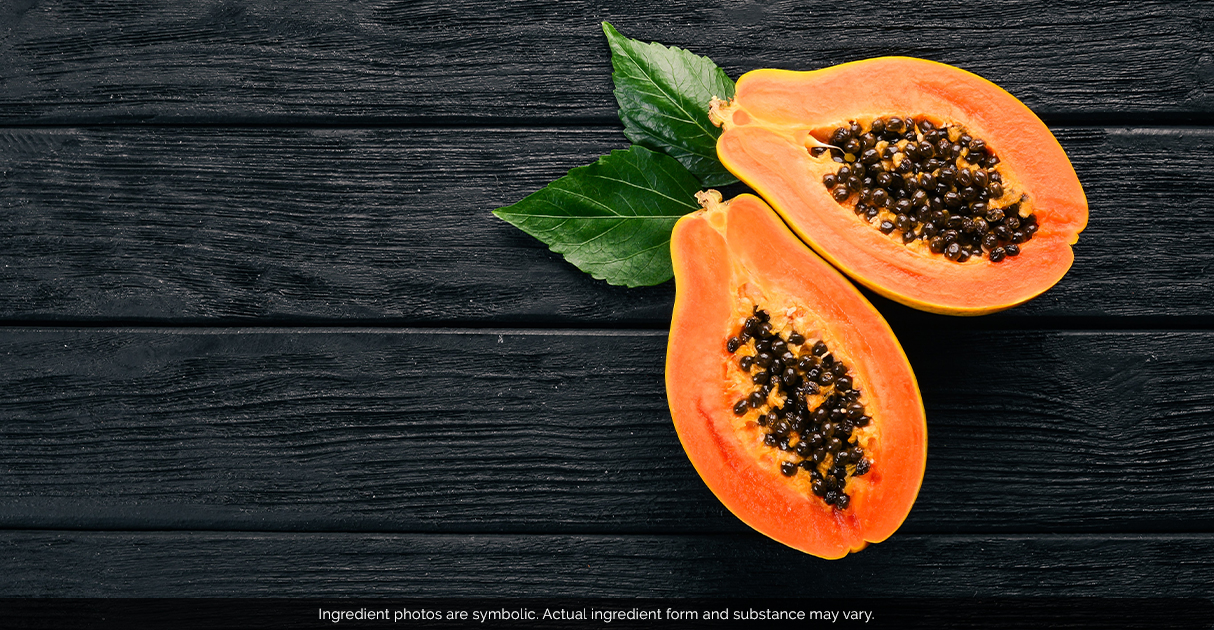 A papaya cut into two halves lying on a wooden table.