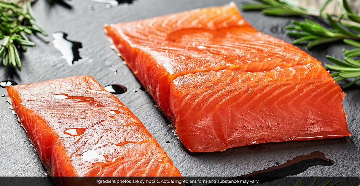 Two slices of raw fish lying on a cutting board.